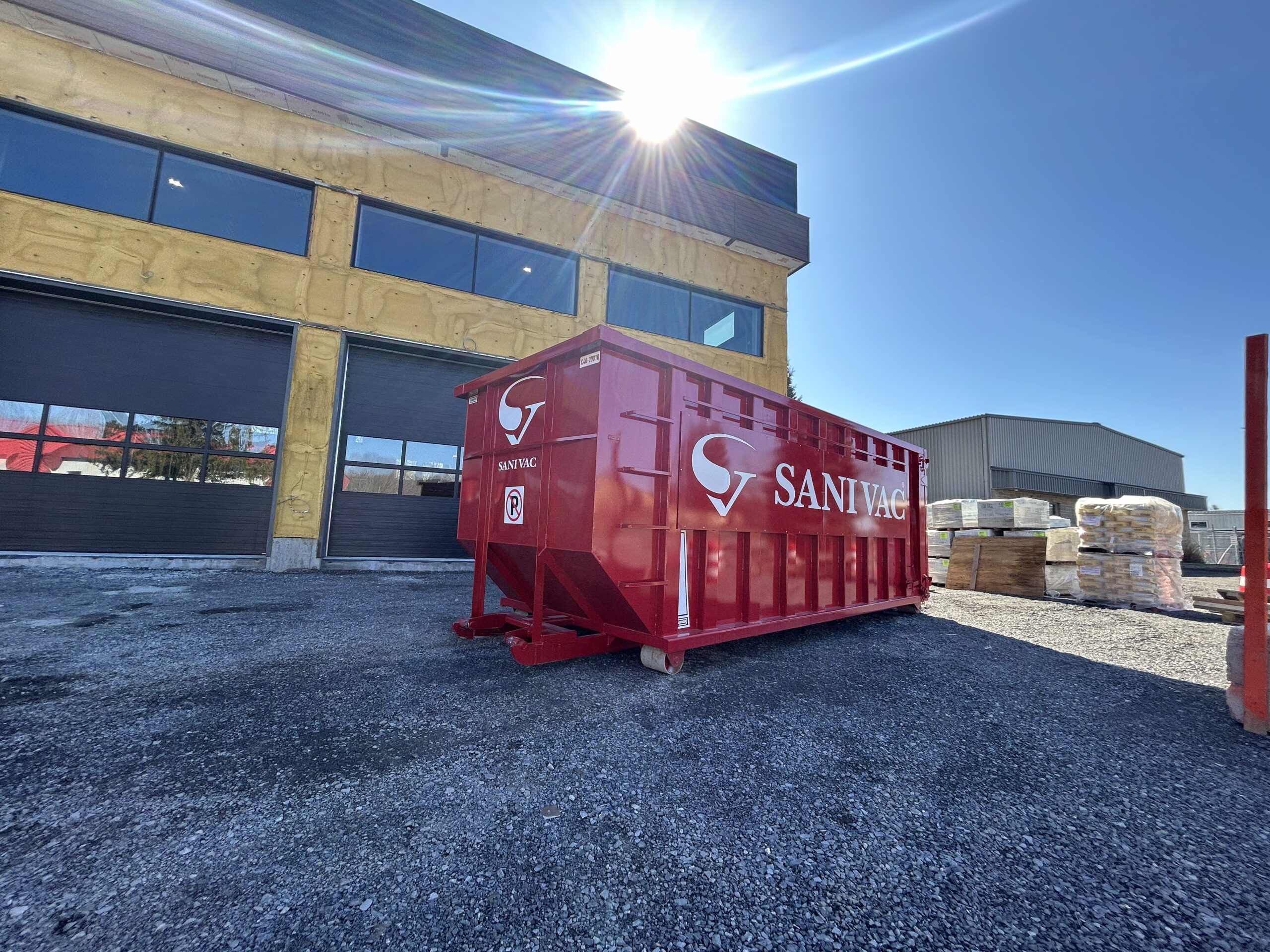 Conteneur Sanivac rouge de 20 verges cubes sur un chantier de construction commercial